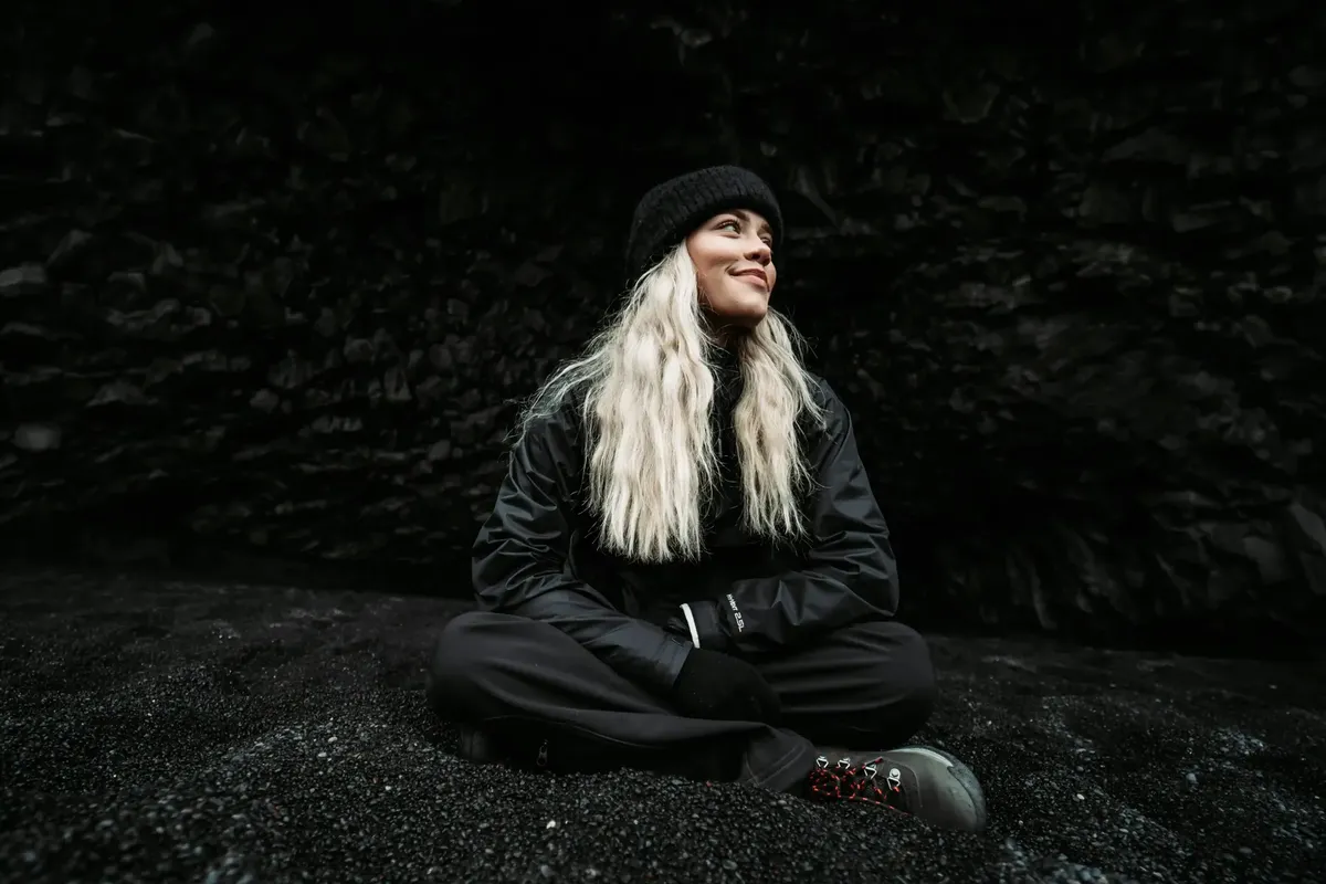 Traveller exploring Reynisfjara basalt cave with sea stacks